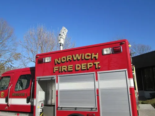 Exterior view of small fire truck showing cab, body compartments, and wheel/tire area.
