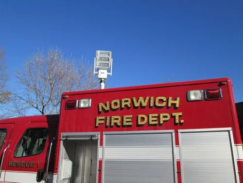 Exterior view of small fire truck showing cab, body compartments, and wheel/tire area.