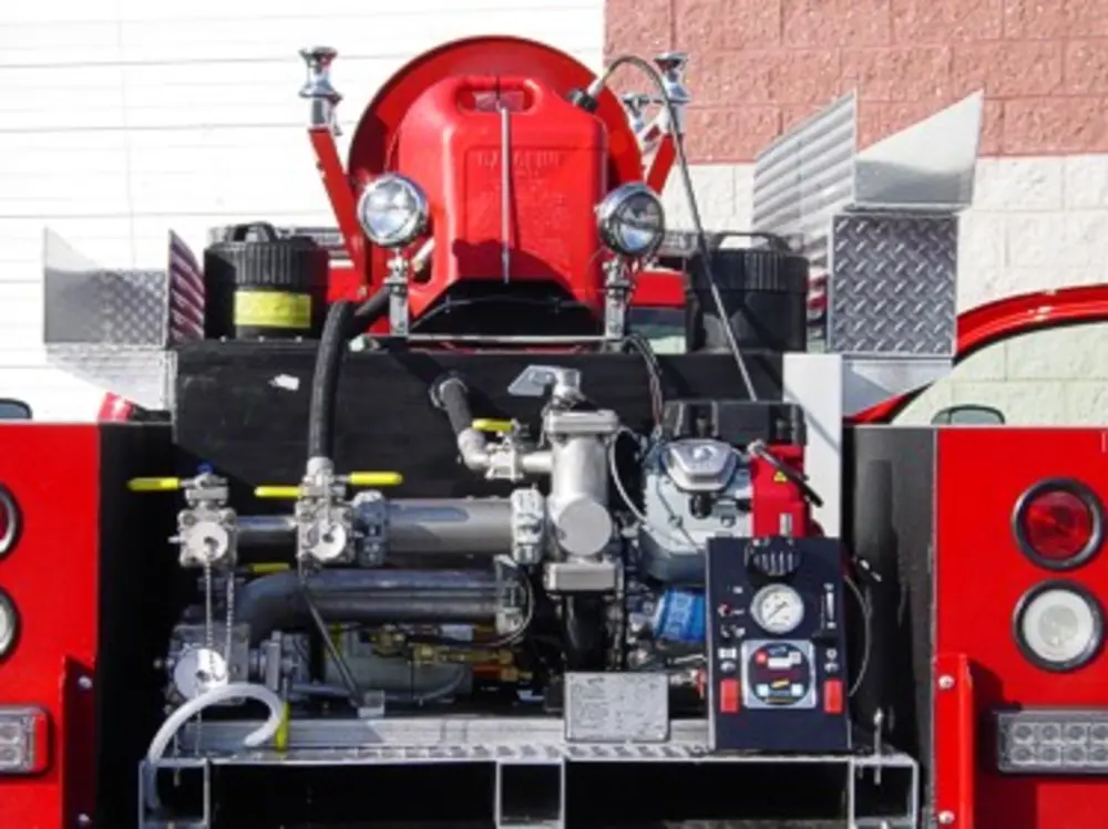 Exterior view of small fire truck showing cab, body compartments, and wheel/tire area.