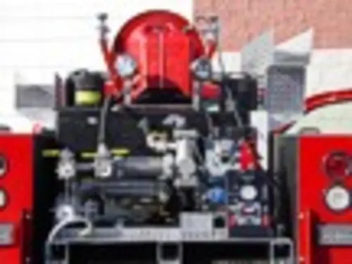 Exterior view of small fire truck showing cab, body compartments, and wheel/tire area.