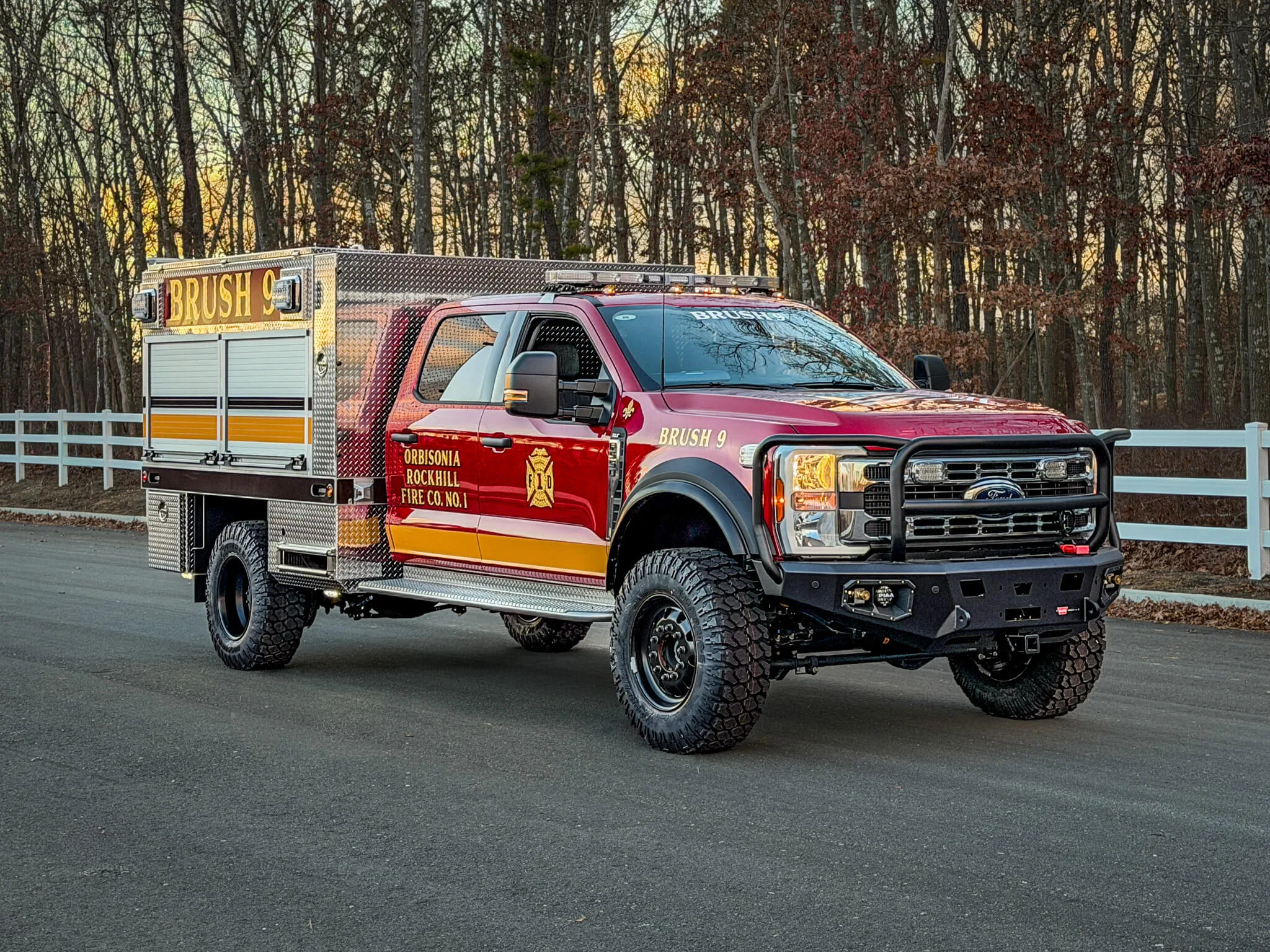 Front driver-side three-quarter view of red brush truck on roadside.