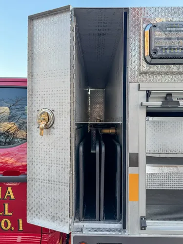 Narrow vertical compartment with mounted cylinder and fittings.