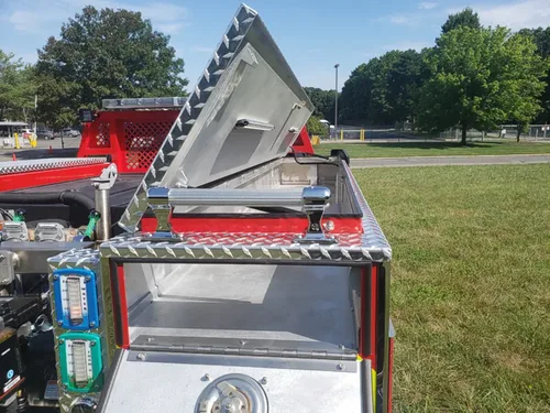 Exterior view of small fire truck showing cab, body compartments, and wheel/tire area.