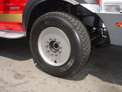 Exterior view of small fire truck showing cab, body compartments, and wheel/tire area.