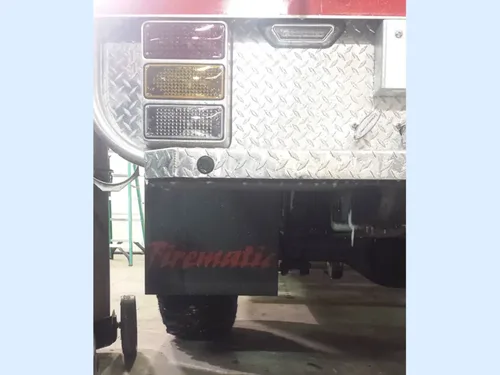 Exterior view of small fire truck showing cab, body compartments, and wheel/tire area.