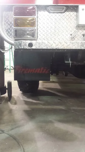 Exterior view of small fire truck showing cab, body compartments, and wheel/tire area.