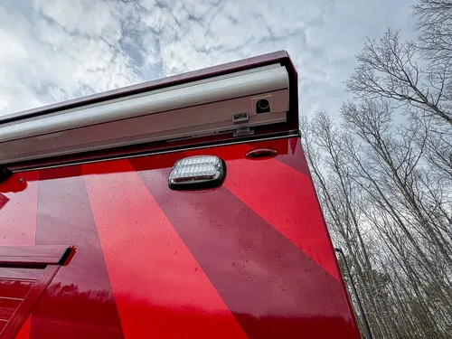 Exterior view of small fire truck showing cab, body compartments, and wheel/tire area.