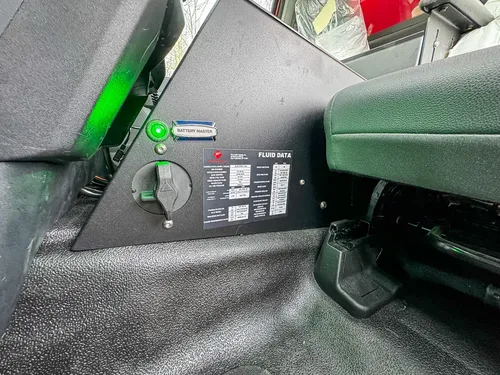 Exterior view of small fire truck showing cab, body compartments, and wheel/tire area.