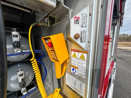 Detail view of yellow control pendant and safety labels inside compartment.