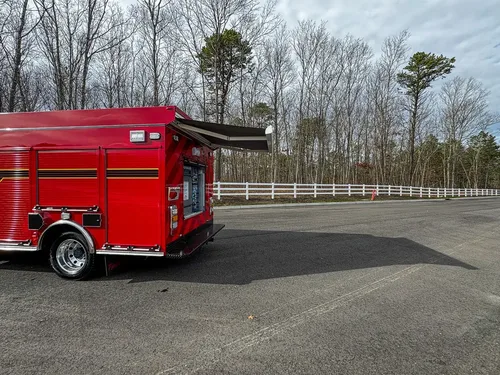Exterior view of small fire truck showing cab, body compartments, and wheel/tire area.