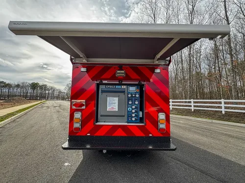 Exterior view of small fire truck showing cab, body compartments, and wheel/tire area.