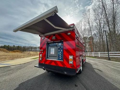 Exterior view of small fire truck showing cab, body compartments, and wheel/tire area.