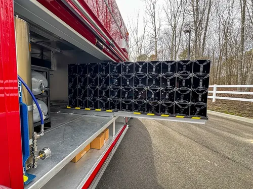 Exterior view of small fire truck showing cab, body compartments, and wheel/tire area.