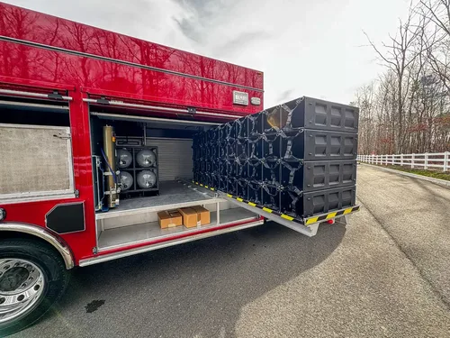 Exterior view of small fire truck showing cab, body compartments, and wheel/tire area.