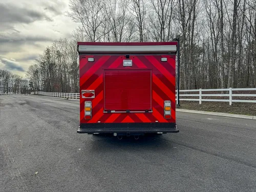 Direct rear view with red chevron striping and rear roll-up door.