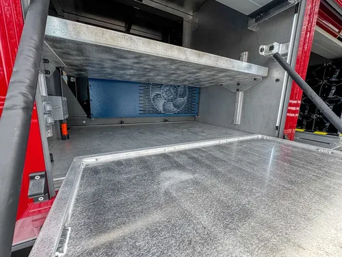 Exterior view of small fire truck showing cab, body compartments, and wheel/tire area.