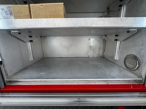 Exterior view of small fire truck showing cab, body compartments, and wheel/tire area.