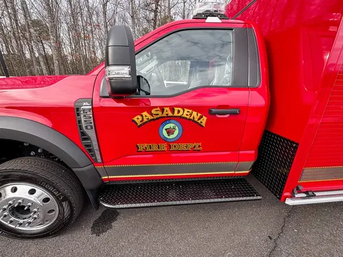 Exterior view of small fire truck showing cab, body compartments, and wheel/tire area.