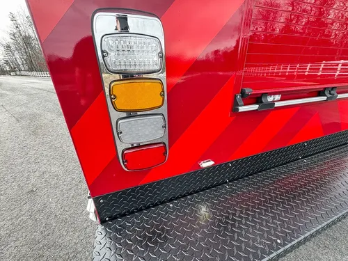 Exterior view of small fire truck showing cab, body compartments, and wheel/tire area.