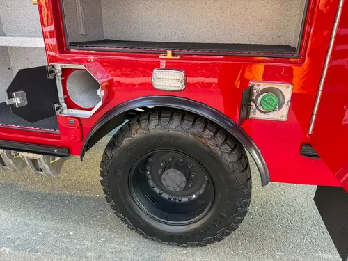 Rear wheel area with utility access doors open, exposing fill ports.