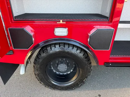 Rear wheel close-up beneath side compartments with access covers closed.