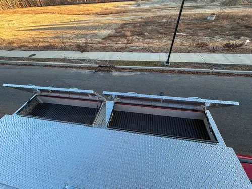 Top-deck view with both rectangular storage hatches open near the side edge.