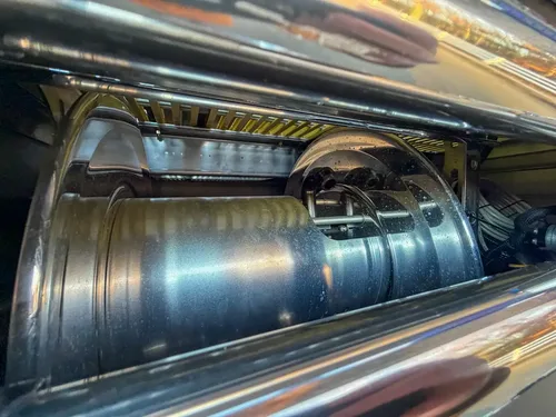 Close-up inside upper rear compartment showing hose reel drum and hardware.