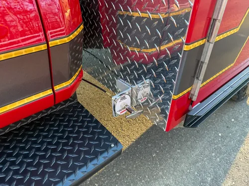 Close-up of side-mounted control valve on diamond-plate body panel above step.