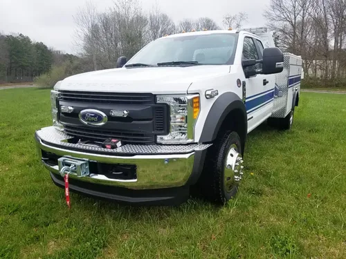 Exterior view of small fire truck showing cab, body compartments, and wheel/tire area.