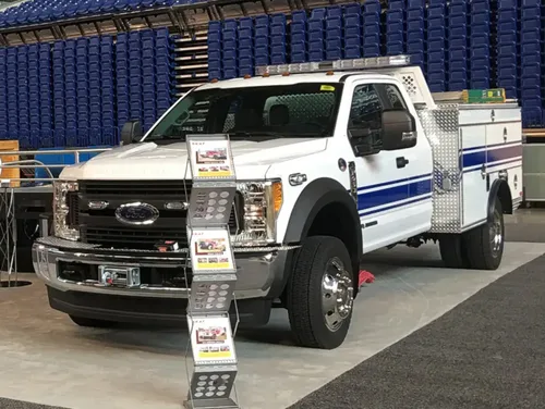 Exterior view of small fire truck showing cab, body compartments, and wheel/tire area.