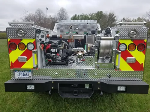 Exterior view of small fire truck showing cab, body compartments, and wheel/tire area.