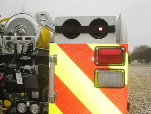 Exterior view of small fire truck showing cab, body compartments, and wheel/tire area.