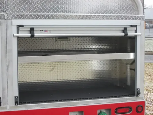 Exterior view of small fire truck showing cab, body compartments, and wheel/tire area.