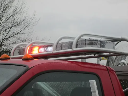 Exterior view of small fire truck showing cab, body compartments, and wheel/tire area.
