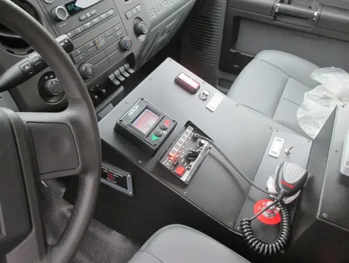 Exterior view of small fire truck showing cab, body compartments, and wheel/tire area.