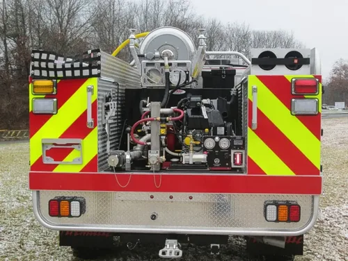 Exterior view of small fire truck showing cab, body compartments, and wheel/tire area.