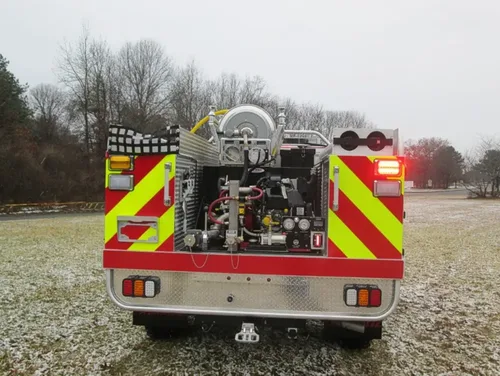 Exterior view of small fire truck showing cab, body compartments, and wheel/tire area.
