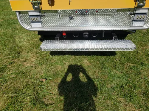 Exterior view of small fire truck showing cab, body compartments, and wheel/tire area.