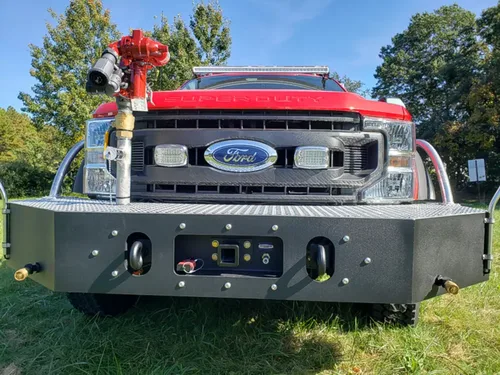 Exterior view of small fire truck showing cab, body compartments, and wheel/tire area.
