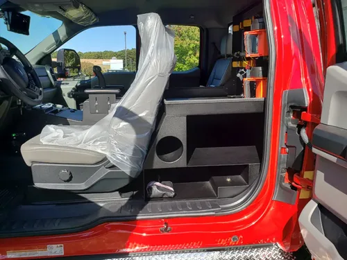 Exterior view of small fire truck showing cab, body compartments, and wheel/tire area.