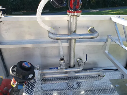 Exterior view of small fire truck showing cab, body compartments, and wheel/tire area.