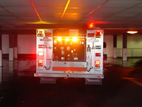 Exterior view of small fire truck showing cab, body compartments, and wheel/tire area.