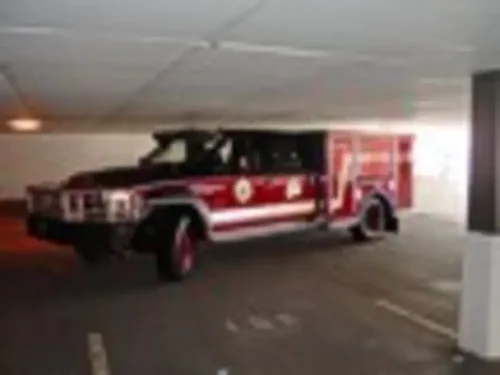 Exterior view of small fire truck showing cab, body compartments, and wheel/tire area.