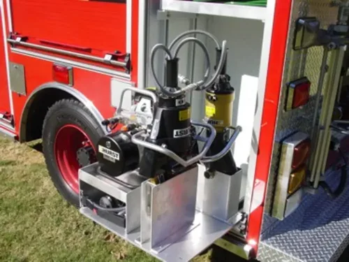 Exterior view of small fire truck showing cab, body compartments, and wheel/tire area.