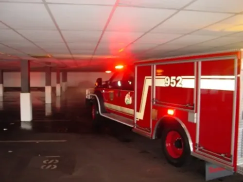 Exterior view of small fire truck showing cab, body compartments, and wheel/tire area.