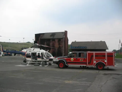 Exterior view of small fire truck showing cab, body compartments, and wheel/tire area.