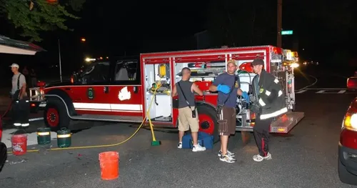 Exterior view of small fire truck showing cab, body compartments, and wheel/tire area.