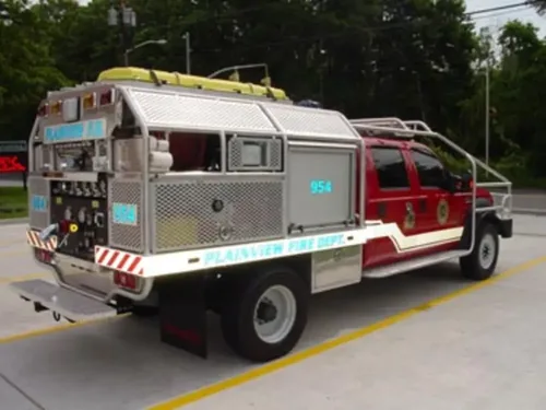 Exterior view of small fire truck showing cab, body compartments, and wheel/tire area.