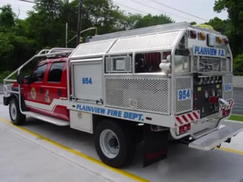 Exterior view of small fire truck showing cab, body compartments, and wheel/tire area.