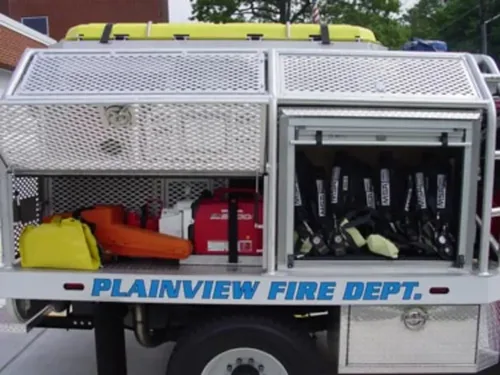 Exterior view of small fire truck showing cab, body compartments, and wheel/tire area.